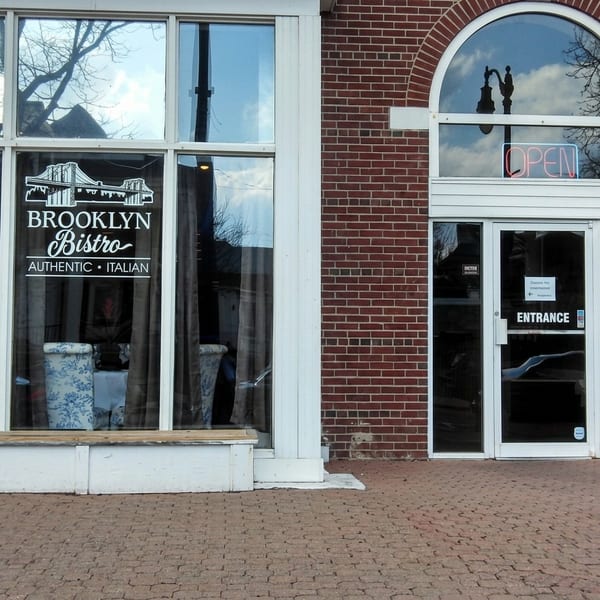 Exterior of Brooklyn Bistro, an authentic Italian restaurant, with a brick facade and an "OPEN" sign.