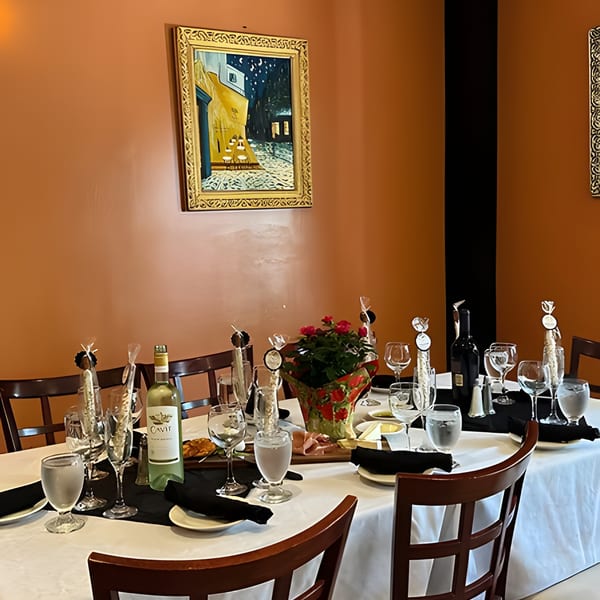 A dining table set with white and red wine, glasses, appetizers, and a floral centerpiece.