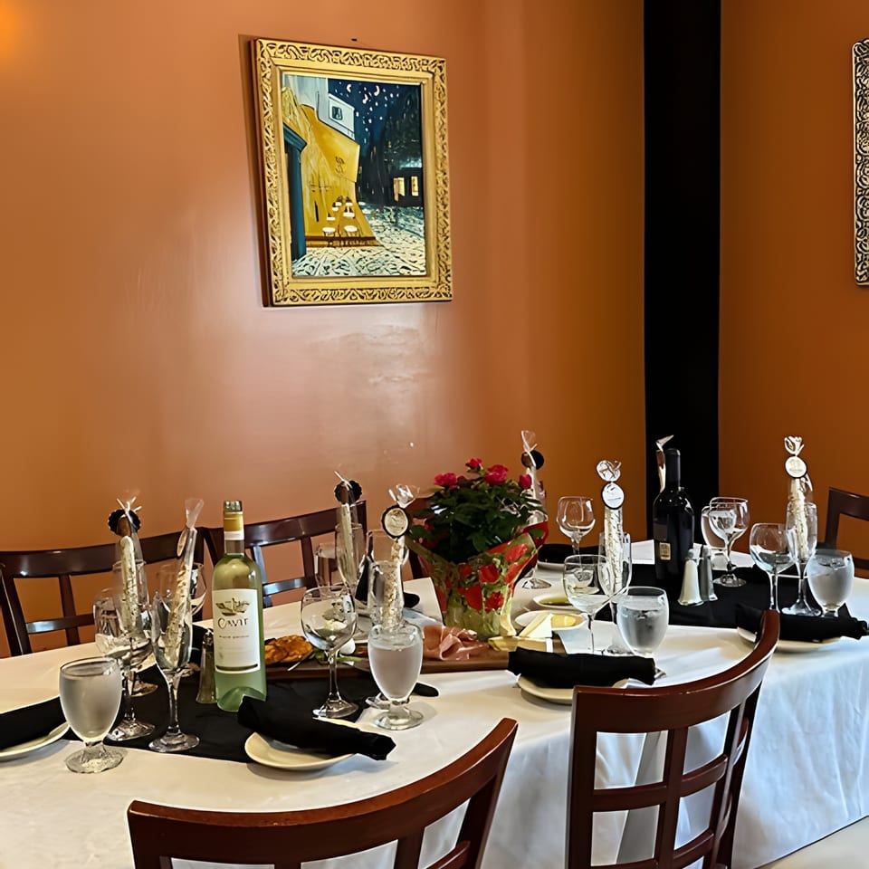 A dining table set with white and red wine, glasses, appetizers, and a floral centerpiece.