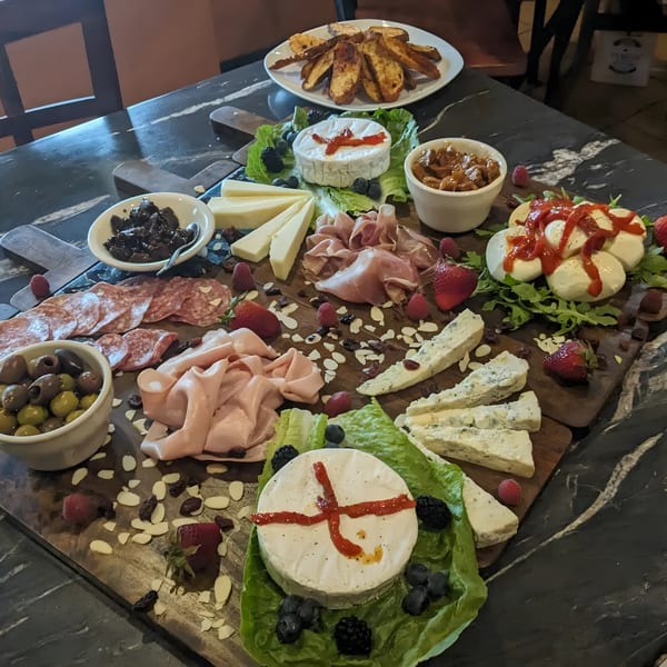 A large charcuterie board filled with cheeses, meats, olives, fruits, and nuts on a dark marble table.